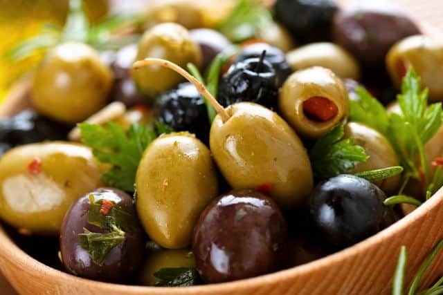 Different kinds of olives on a bowl.