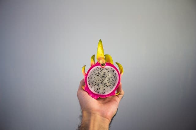 A person holding a sliced dragon fruit