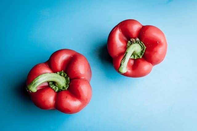 Two red raw bell peppers.