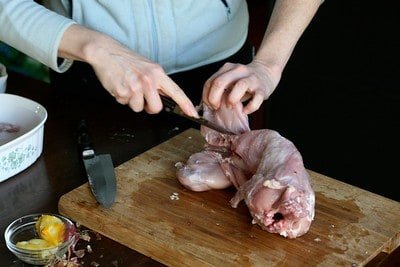 A man cutting a rabbit meat to be cooked What Does Rabbit Meat Taste Like?